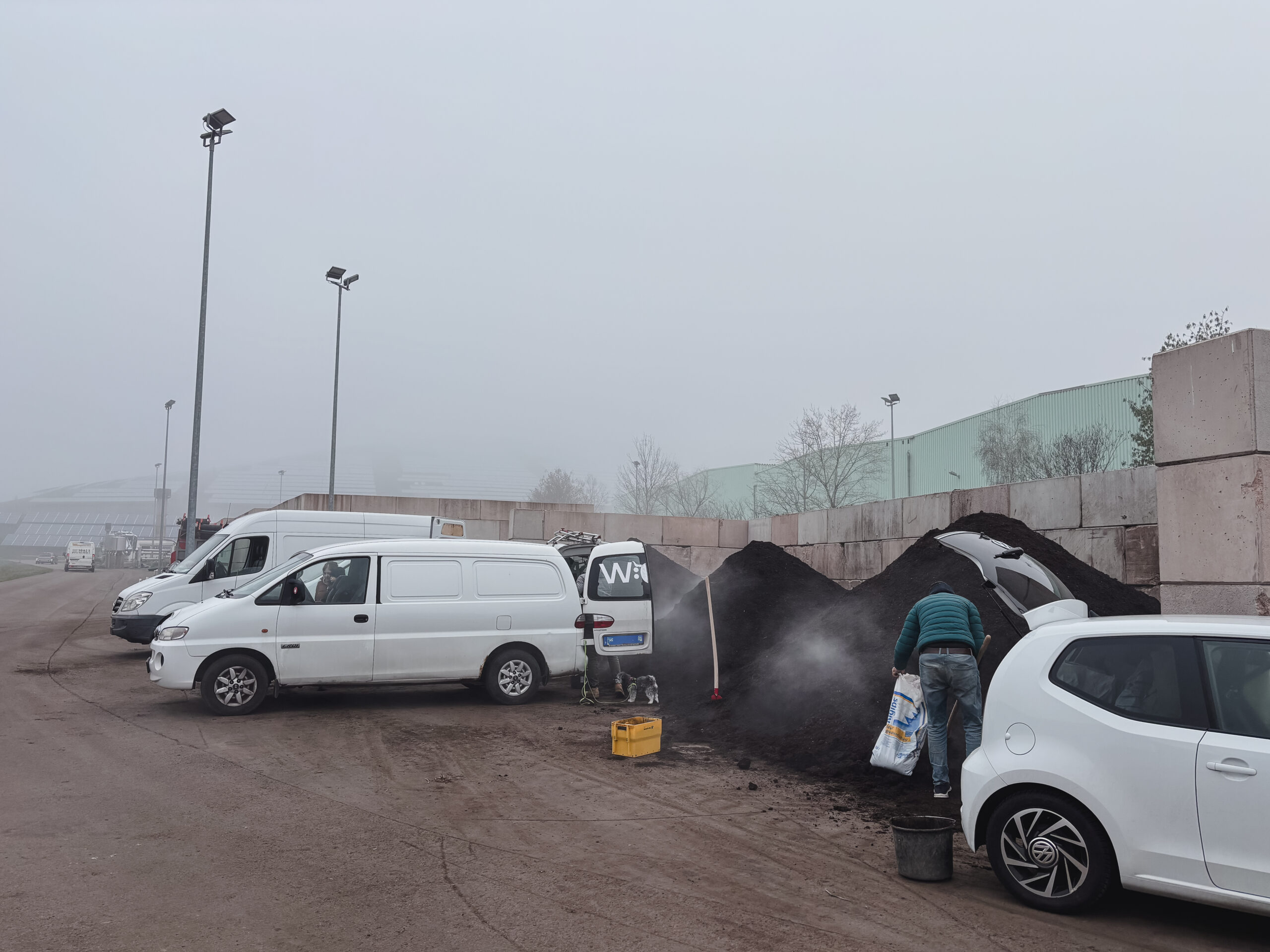 Komposttag 2026 Komposttag: Personen füllen Kompost in Säcke neben weißen Lieferwagen.